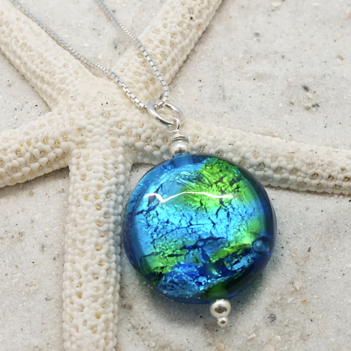Hand-blown glass pendant by Sailorgirl Jewelry with green and blue foil inside.